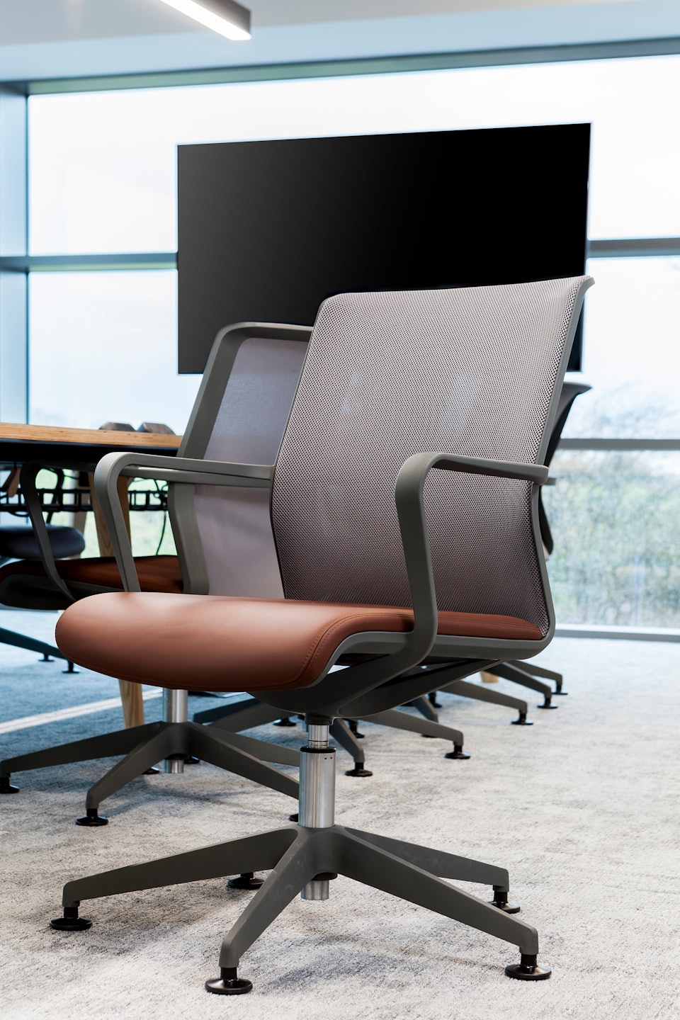 Ergonomische Stühle sind um einen Holztisch in einem Konferenzraum angeordnet.