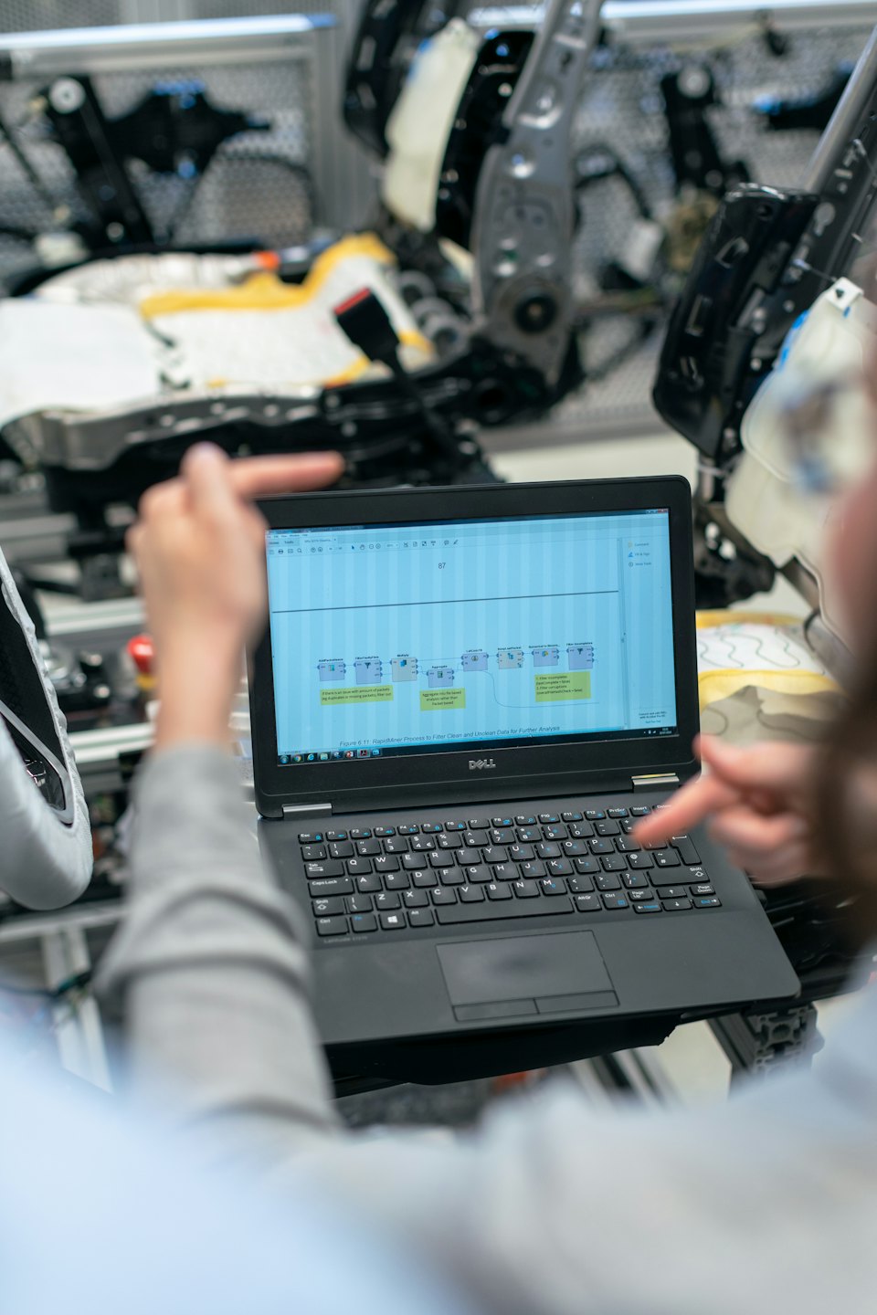 Zwei Personen, die einen Datenflussdiagramm auf einem Laptop-Bildschirm überprüfen.